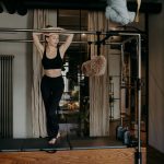 Young slim caucasian female resting on bar of pilates cadillac reformer