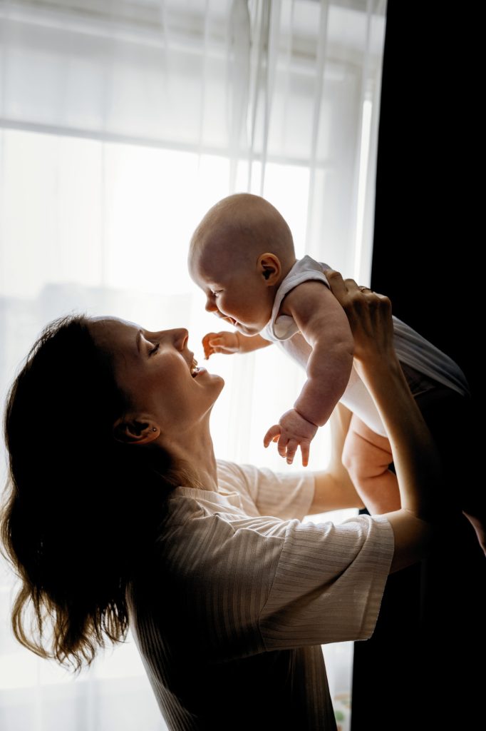 Mom holds a laughing baby in her arms, happy childhood
